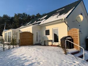 a white house with a snow covered driveway at Ferienhaus Köhler Am Achterwasser incl Bootsvermietung in Lütow