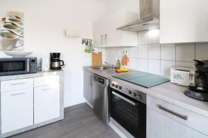 eine Küche mit weißen Schränken und einem Herd mit Backofen in der Unterkunft Ferienhaus Achterwasser in Lütow