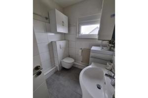 ein weißes Badezimmer mit Toilette und Waschbecken in der Unterkunft Ferienhaus Achterwasser in Lütow + 21 Fotos