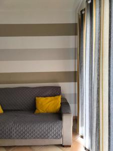 a couch with a yellow pillow on a striped wall at La Caletta di Dany in Castelsardo