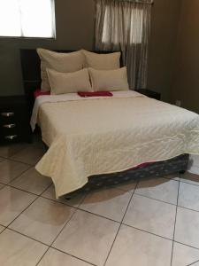 1 dormitorio con 1 cama grande y edredón blanco en Ebony Lounge Hotel and Event Center en Pretoria