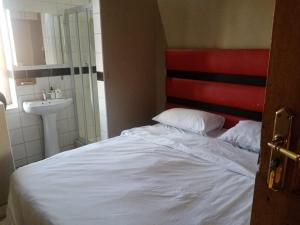 um quarto com uma cama branca e um lavatório em Ebony Lounge Hotel and Event Center em Pretoria