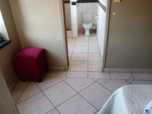 uma casa de banho com WC e piso em azulejo em Ebony Lounge Hotel and Event Center em Pretoria