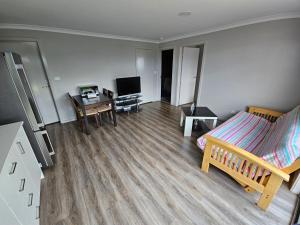 Zimmer mit einem Bett, einem Schreibtisch und einem TV in der Unterkunft Brand new self-contained one bedroom unit in Queanbeyan