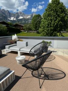 a patio with a chair and a couch and mountains at GOING TRIPLE A apartments NORTH in Going am Wilden Kaiser