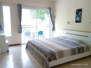 a bedroom with a bed and a large window at Belinda Home in Ko Si Chang
