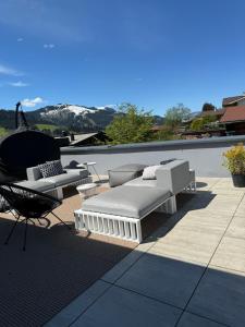 eine Terrasse mit Sofas und einem Stuhl auf dem Dach in der Unterkunft GOING TRIPLE A apartments NORTH in Going