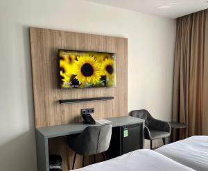 a hotel room with a desk and a picture of a sunflower at OZO Hotels Antares Airport in Hoofddorp