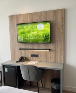 Habitación con escritorio y TV en la pared. en OZO Hotels Antares Airport en Hoofddorp