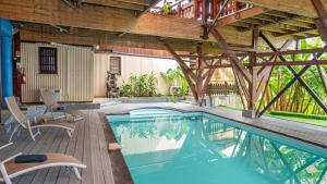 een binnenzwembad met een houten terras en een gebouw bij Jade hôtel and spa in Bandrélé