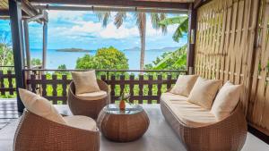 a balcony with wicker chairs and a table and the ocean at Jade hôtel and spa in Bandrélé