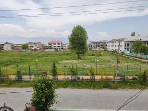 a field with a tree and buildings in the background at Mir manzil in Srinagar