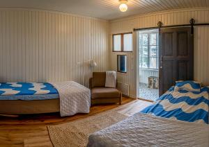 a bedroom with two beds and a chair and a window at Ahoniemi - Kellankoski in Rossi