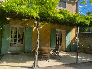 d'une terrasse avec une table, des chaises et un arbre. dans l'établissement Le Mas de Trévouse, à Saint-Saturnin-lès-Avignon