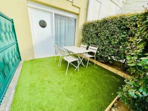 a table and chairs on a patio with green grass at Le Bel Iris - Accès direct plage in Châtelaillon-Plage
