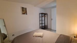 ein weißes Schlafzimmer mit einem Bett und einem Handtuch darauf in der Unterkunft Appartement cool en plein centre de Libourne in Libourne