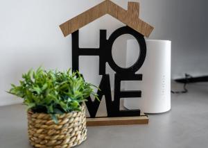 Un cartel de casa junto a una taza y una planta. en LA88 Cityway Apartment 4, en Il-Gżira