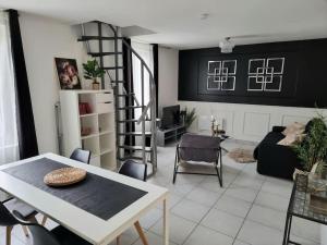 a living room with a table and a spiral staircase at Maison aux portes de Tours in Saint-Pierre-des-Corps