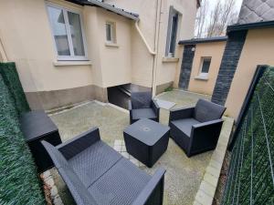 eine Terrasse mit Stühlen und Tischen und ein Gebäude in der Unterkunft Maison aux portes de Tours in Saint-Pierre-des-Corps