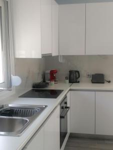 eine weiße Küche mit weißen Schränken und einer Spüle in der Unterkunft casaeudokia in Apóllona