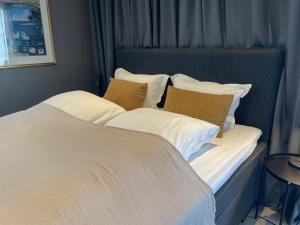 a large bed with white sheets and brown pillows at Suite i gjestehus, nær sentrum in Sandefjord