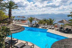 a pool with chairs and umbrellas and the ocean at Sunlight Elounda - Adults only Hotel "by Checkin" in Agios Nikolaos