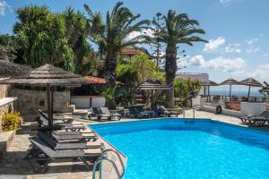 una piscina con sillas, sombrillas y palmeras en Sunlight Elounda - Adults only Hotel "by Checkin" en Ágios Nikólaos