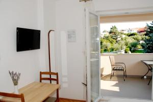 a living room with a sliding glass door and a table and chairs at Studio Ruzmarin in Krk