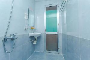 biała łazienka z umywalką i prysznicem w obiekcie Motel Tulip w mieście Da Nang