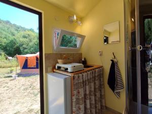 a small kitchen with a refrigerator and a microwave at Familytent "Kukucka" with private sanitary facilities - Holidayfarm Natural Slovakia in Modrý Kameň