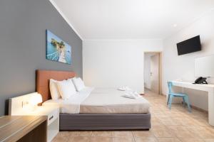 a white bedroom with a bed and a desk at Cameo Beach Resort in Laganas