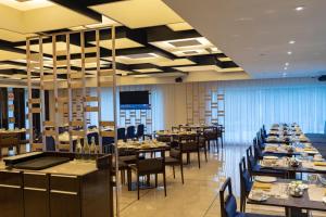 RPJ Hotel Rajkot في راجكوت: غرفة طعام مليئة بالطاولات والكراسي
