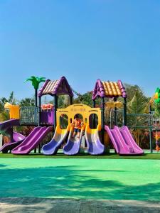 un parque infantil con un tobogán púrpura y amarillo en Kokomo Sunset Resort en Gazipur