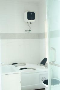 a white bathroom with a toilet and a tv on the wall at Mannda Villa Apartments in Aja