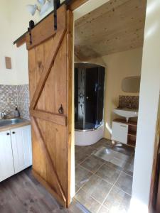 a door in a bathroom with a shower and a sink at Tinyfarm "Stará Láska" - Holidayfarm Natural Slovakia in Modrý Kameň