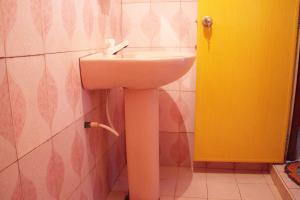 un lavandino bianco in un bagno con porta gialla di Sagopearl Guest a Mirissa