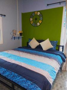 1 dormitorio con 1 cama grande y reloj en la pared en Khao thalu guest house, en Ban Muang Wan