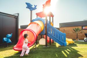 a little girl playing on a slide at a playground at RResort Holiday Homes - HEATED Swimming Pool & Sauna in Rewal +23 photos