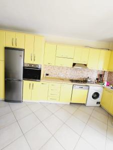 a kitchen with yellow cabinets and a refrigerator at Summer apartments Shengjin in Shëngjin