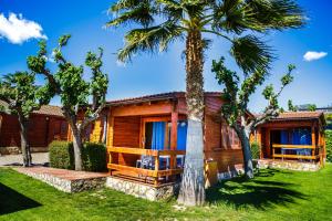 una casa de madera con palmeras delante en Camping La Llosa, en Cambrils