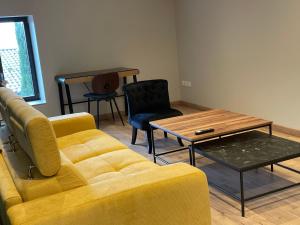 sala de estar con sofá amarillo y mesa en Au Petit Bonheur chez Bambina en Leynes