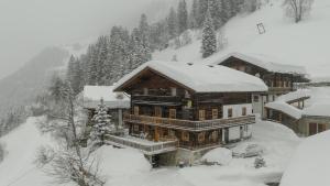 ein großes Haus mit Schnee in den Bergen in der Unterkunft Ferienwohnungen-Schett in Sankt Veit in Defereggen