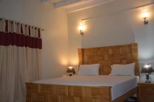 a bedroom with a large bed with white sheets and two lamps at Hanaly Wood Resort & Cafe in Gilgit