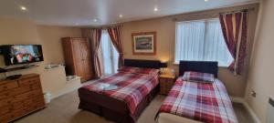 a bedroom with two beds and a flat screen tv at Town House B & B in Skipton