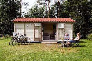 un hombre y una mujer sentados frente a una casita en RCN Vakantiepark de Roggeberg en Appelscha