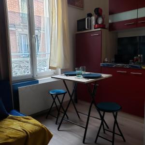 a small kitchen with a table and two stools at Studio cozy - Proche Paris, Métro, salles de concert et Disneyland in Montreuil