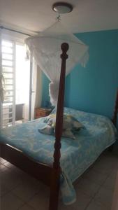 un letto a baldacchino in una camera blu di Résidence de la Baie : Superbe appartement a Le Marin