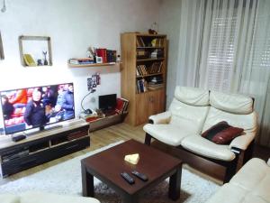 a living room with a white chair and a tv at LUX Apartman in Leskovac