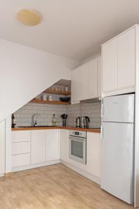 a kitchen with white cabinets and a white refrigerator at Cozy Residence in Astypalaia Town