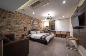 a bedroom with a bed and a brick wall at Hotel Cube in Incheon